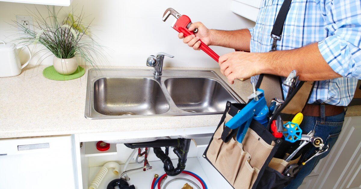 a man is fixing a sink with a wrench