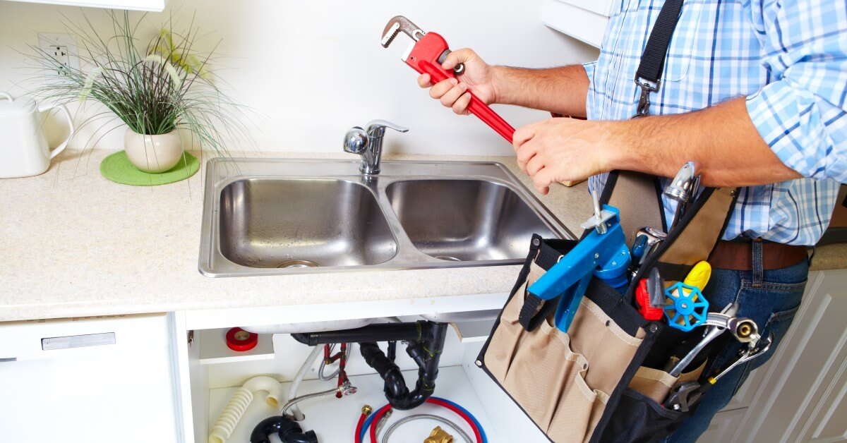 a man is fixing a sink with a wrench