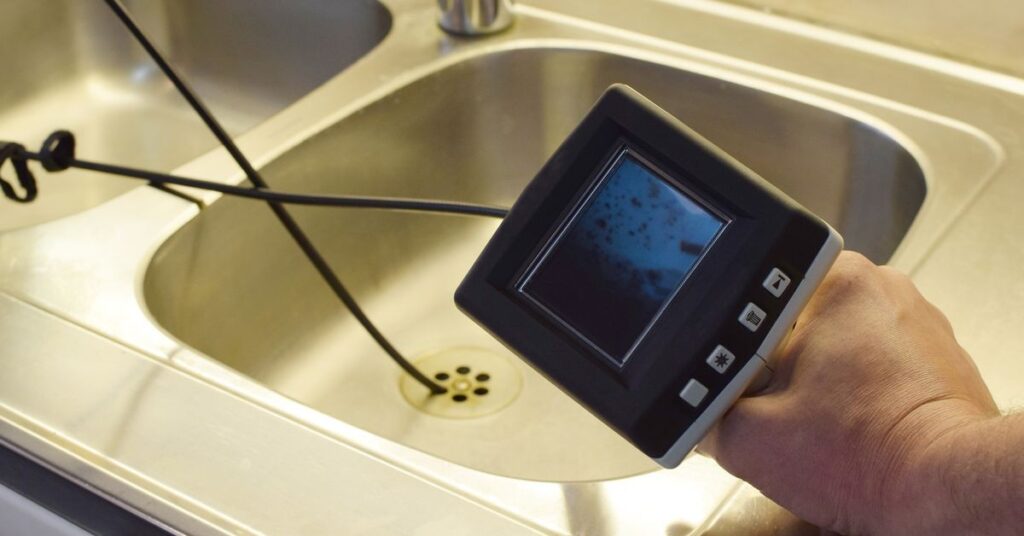 person holding a device over a sink
