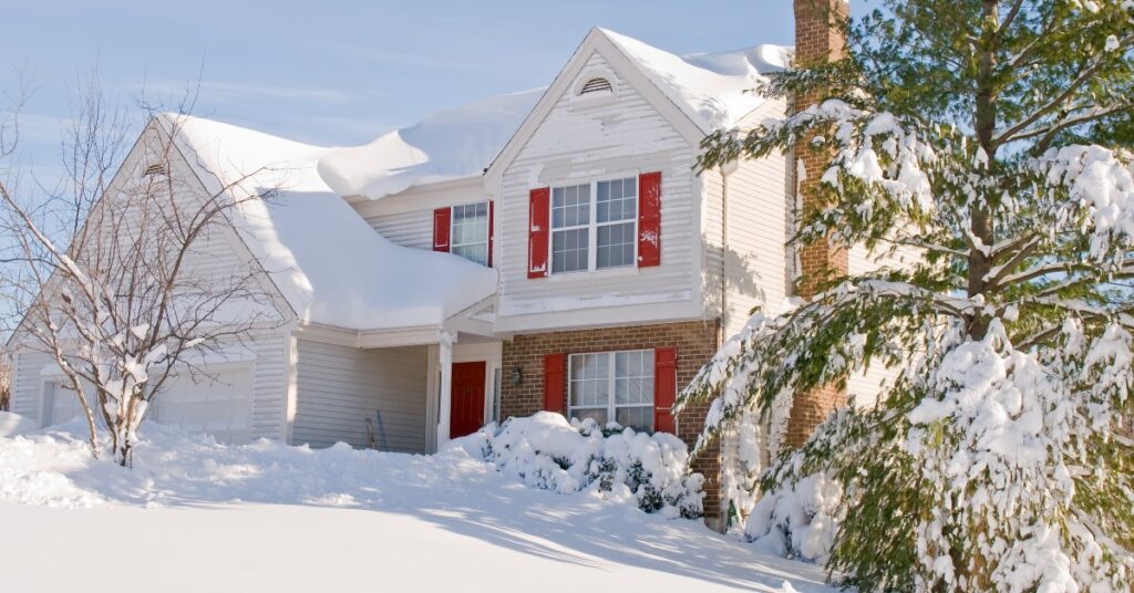 a white house with red shutters is covered in snow