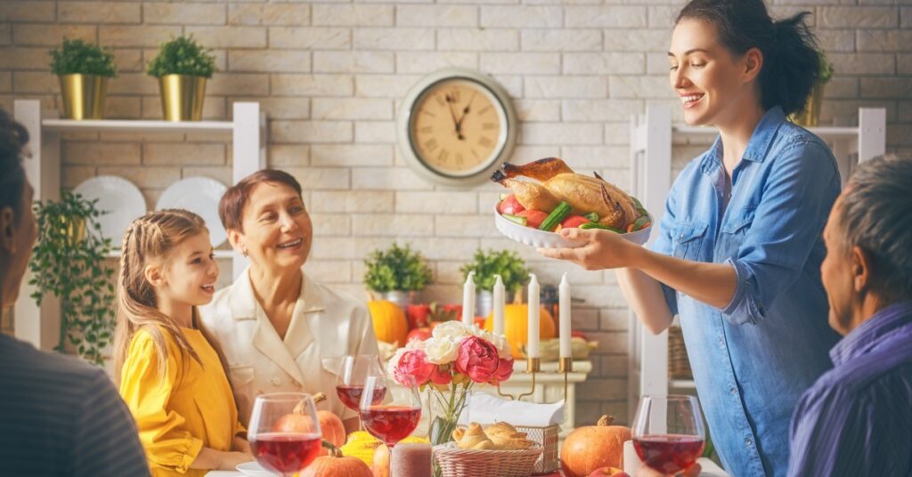 a woman is serving a turkey to a family at a table