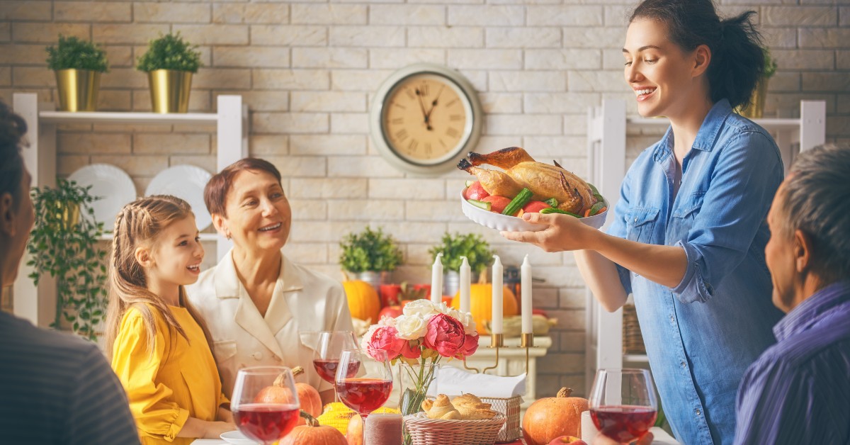 a woman is serving a turkey to a family at a table