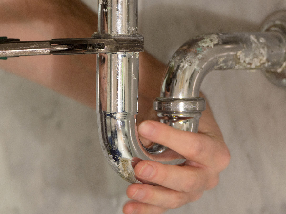 an exposed pipe with someone tightening a bolt