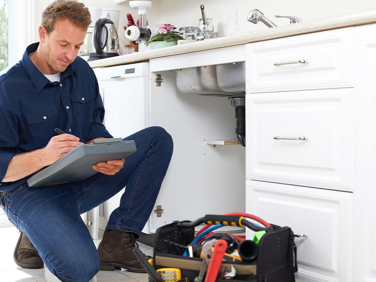 a plumber writing on a clipboard near a sink