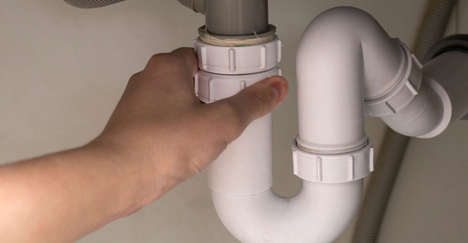 a person is fixing a sink pipe with their hand