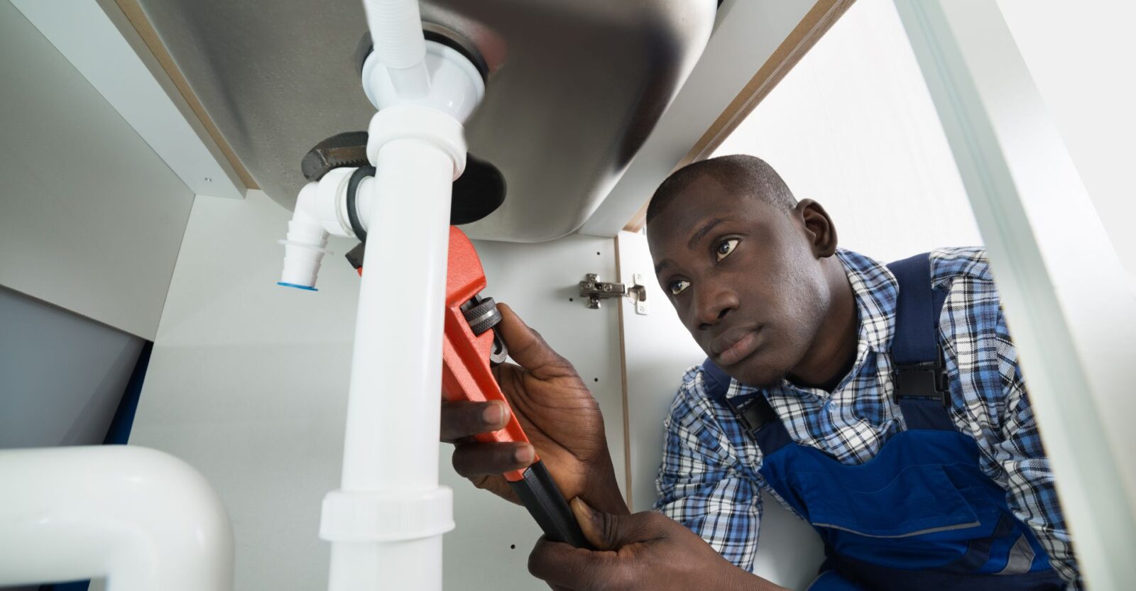 a man is fixing a sink with a wrench