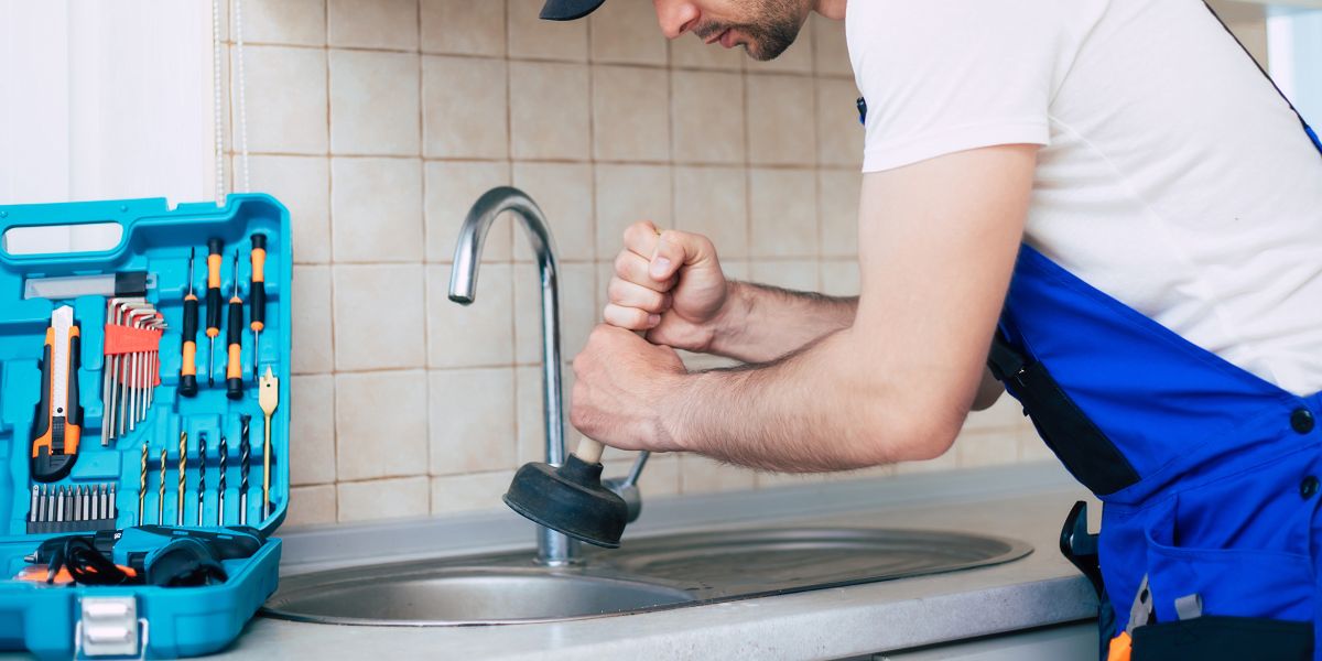 a man in a blue apron is working on a sink