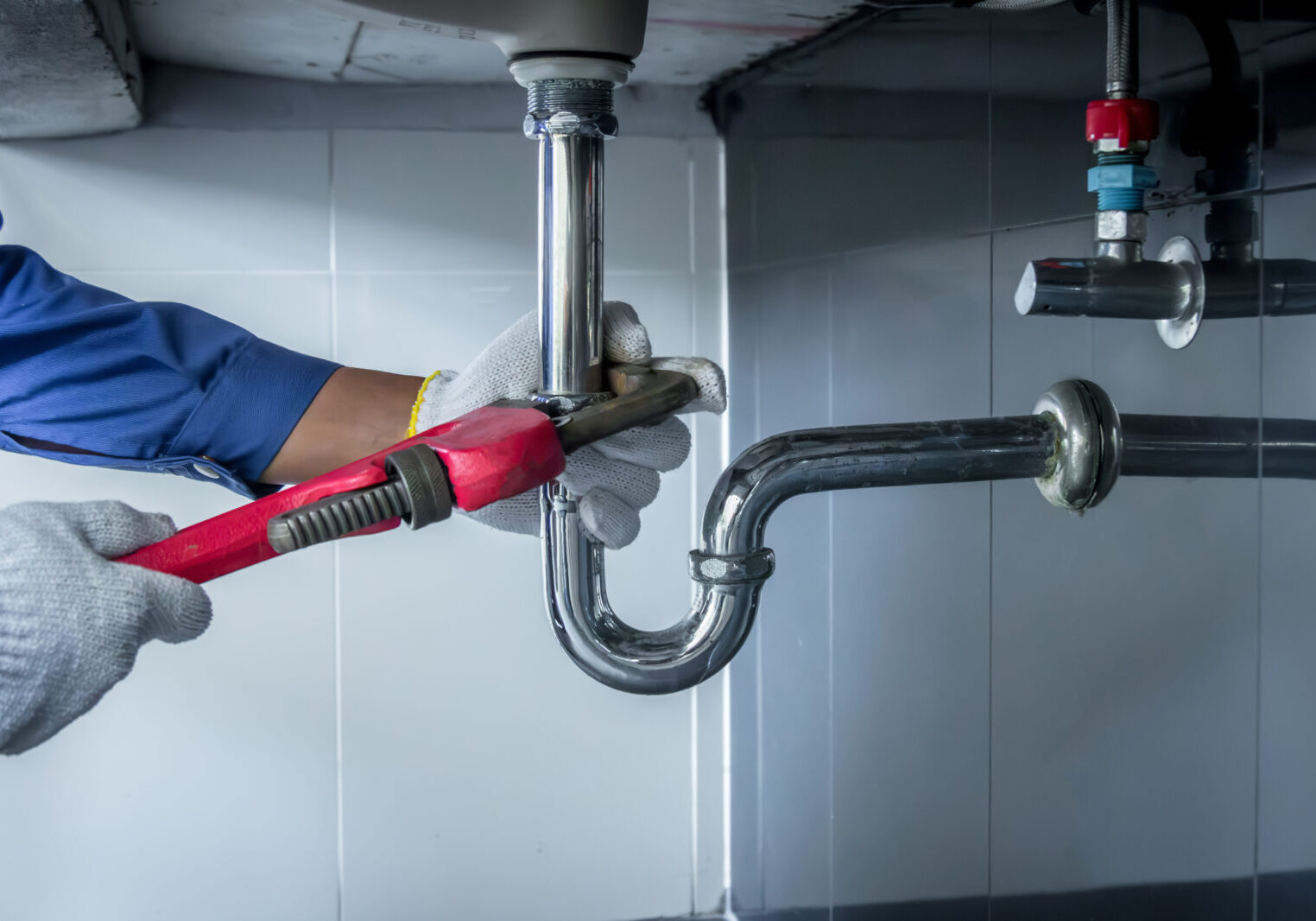 Plumber hands holding wrench doing repairing work at the sink and clogged pipe in bathroom carefully